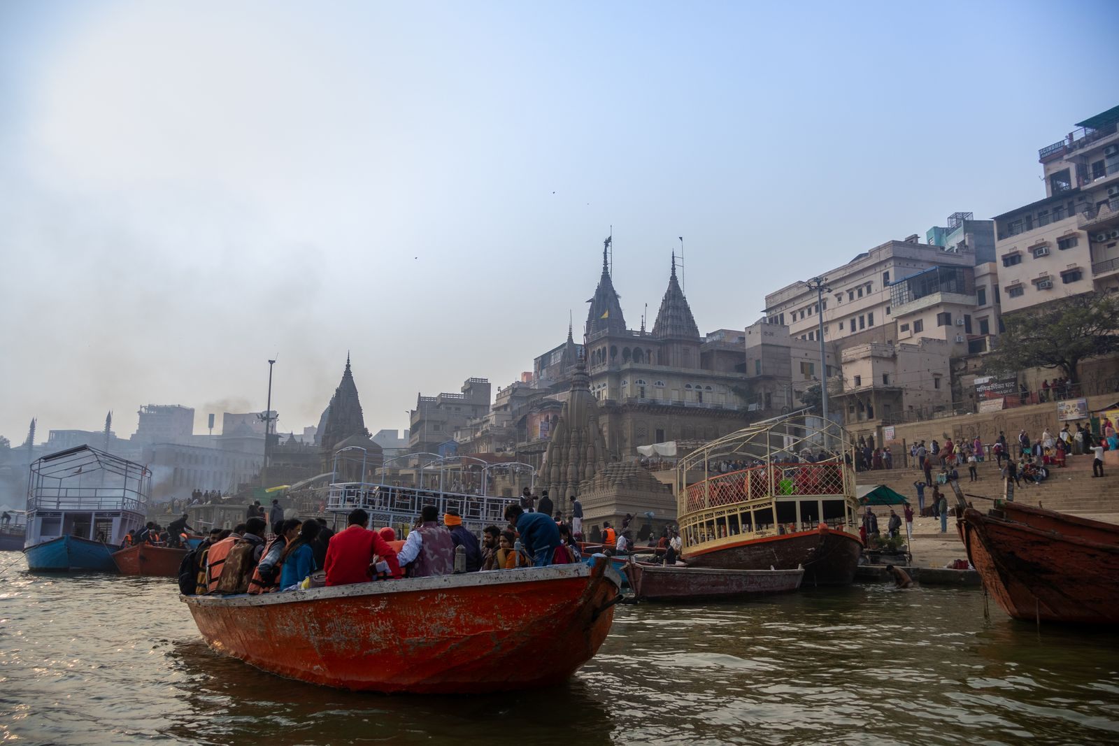 Boats full of visitors on the Ganges below the temples and ghats of Varanasi, the classic finale of a Ganges river cruise